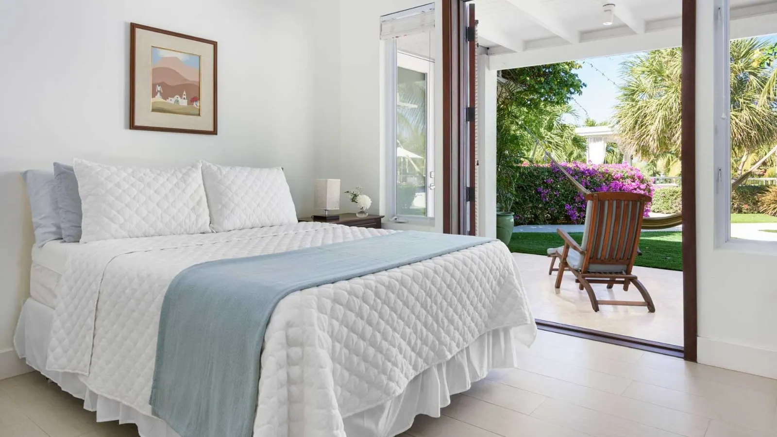 Bedroom Three, queen bed beside floor-to-ceiling doors onto the garden.